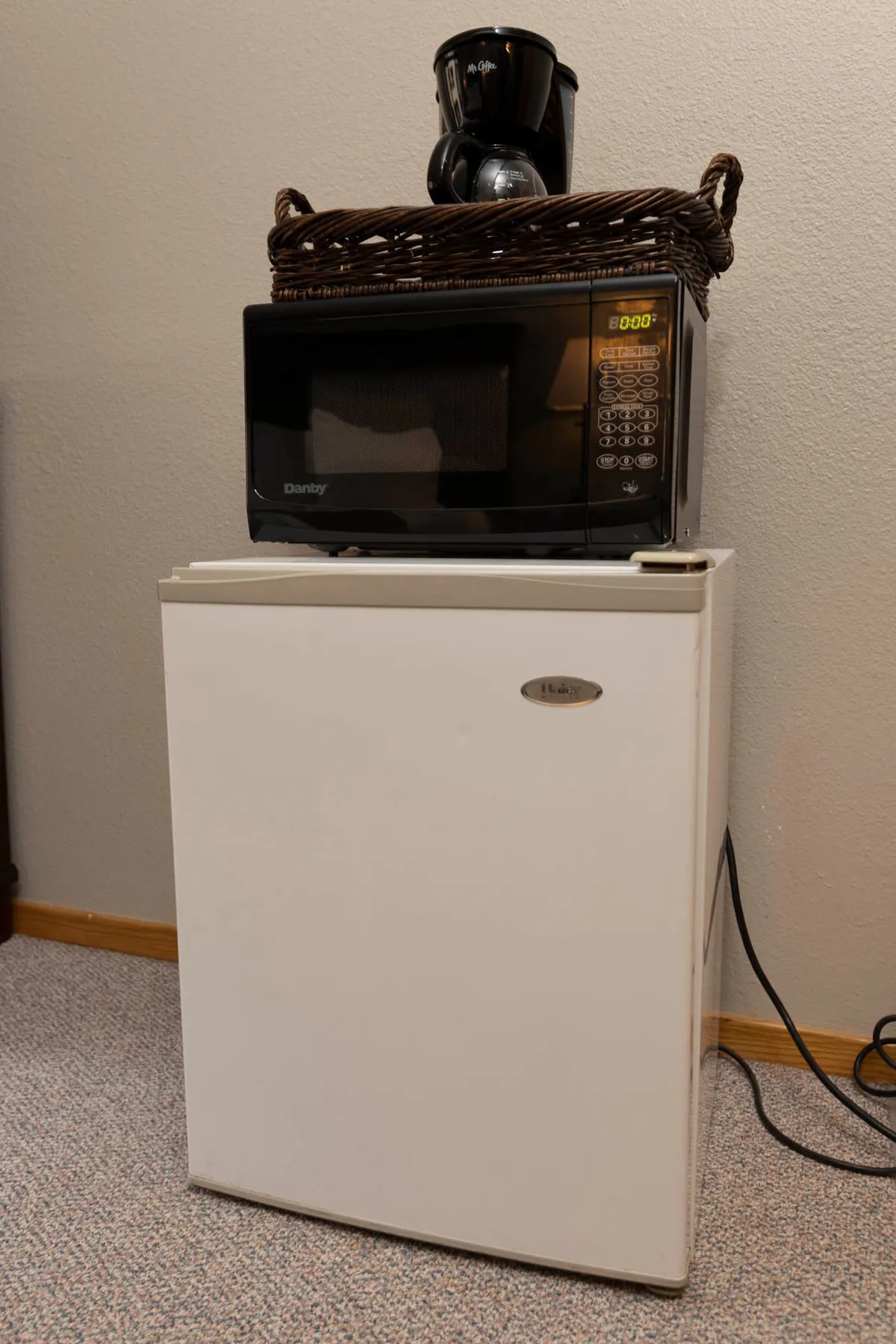 A compact kitchen vignette featuring a microwave, mini fridge, and coffee maker. The setup suggests convenience for quick breakfasts, snacks, or sharing coffee with friends, focusing on the more casual side of dining.