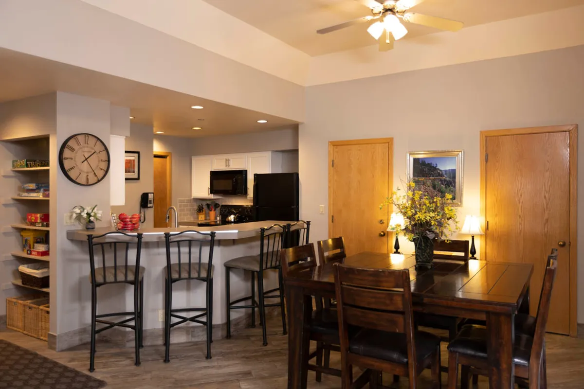 This image shows a warm, inviting dining area complete with a large table set for meals, a nearby bar counter, and tasteful decor including a floral centerpiece. The layout is open and seamlessly connects to the living space, emphasizing communal dining and shared experiences.