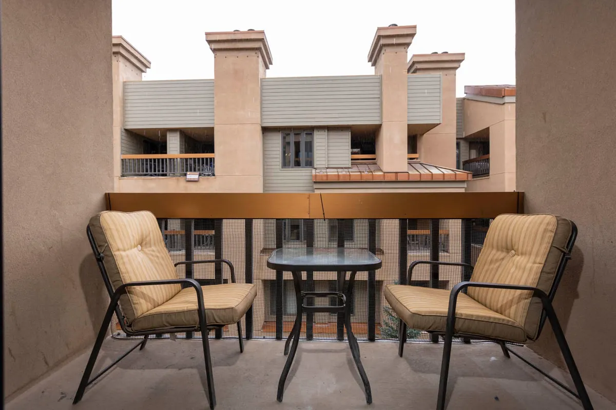 A relaxed outdoor balcony scene featuring comfortable furniture, a view of adjacent buildings, and the promise of enjoying morning coffee or evening stargazing. The ambiance is tranquil and leisurely, perfect for unwinding after a day of adventure.